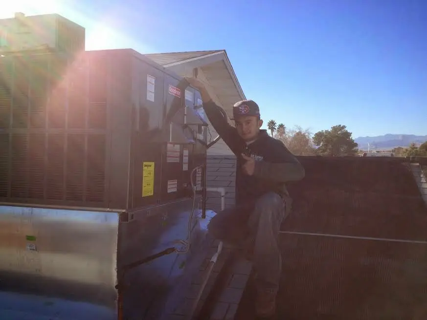 HVAC technician performing Air Duct Cleaning on a rooftop unit in Alexandria